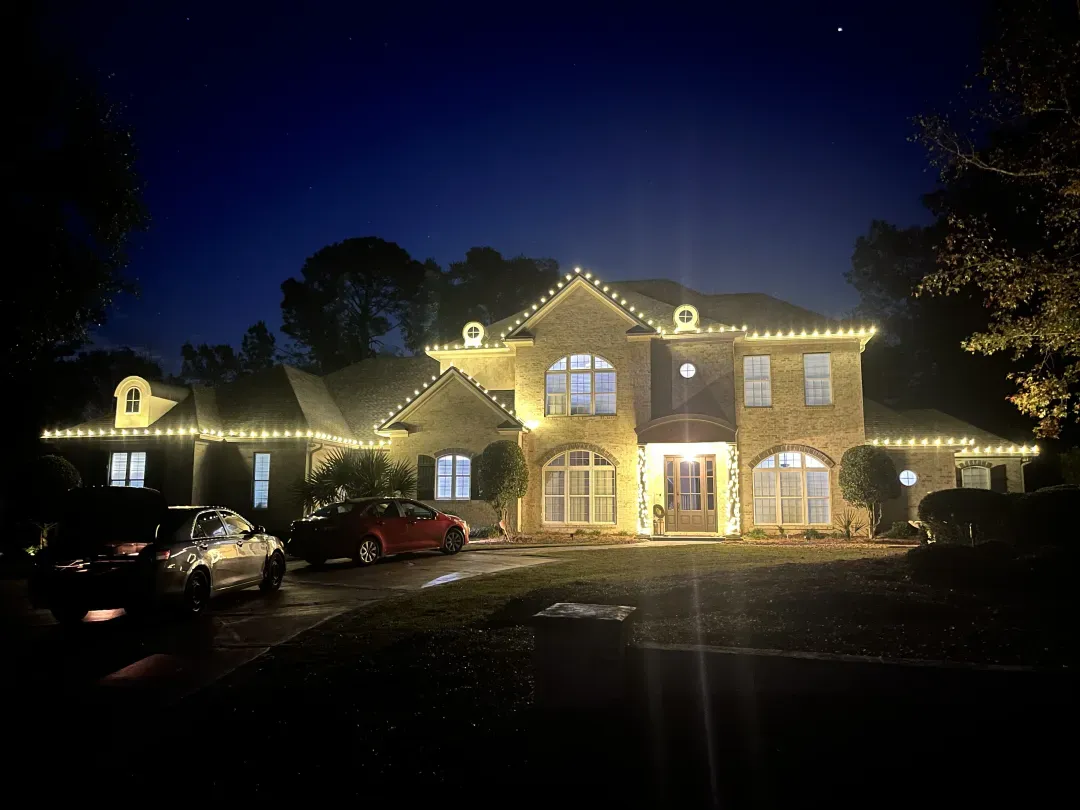 Warm white Christmas lights outlining a home's roofline