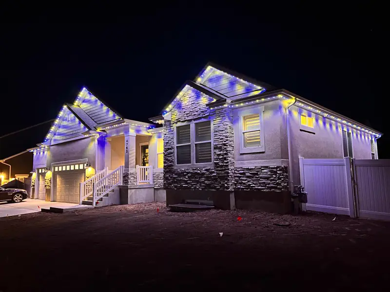 Permanent RGB lights along the gables of a stone-front home
